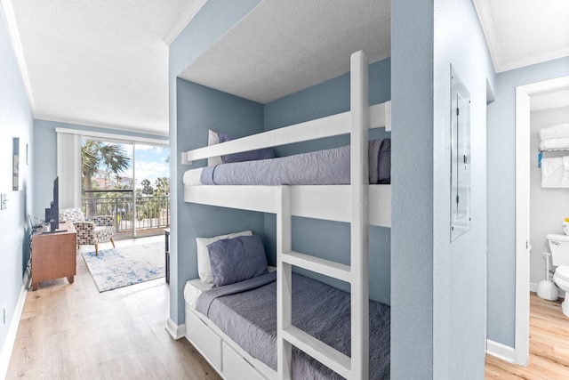 bedroom with ensuite bath, a textured ceiling, light hardwood / wood-style floors, and access to outside