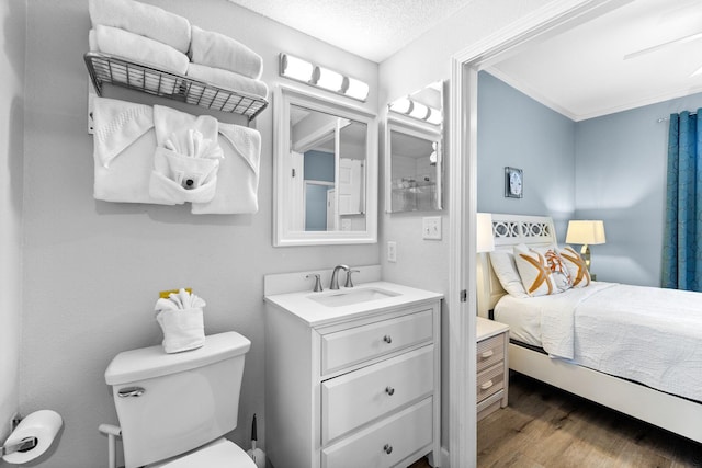 bathroom with vanity, toilet, hardwood / wood-style flooring, and crown molding