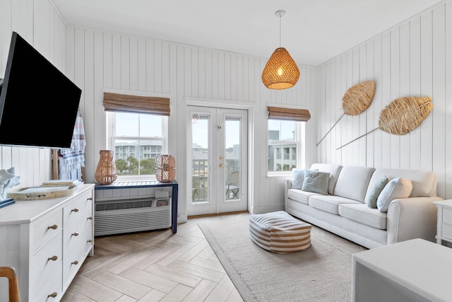 living room with french doors, light parquet flooring, and wooden walls