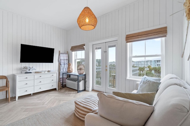 living room with wood walls, french doors, and light parquet flooring