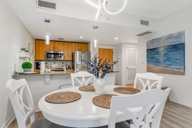 dining space featuring light hardwood / wood-style flooring, sink, and a notable chandelier