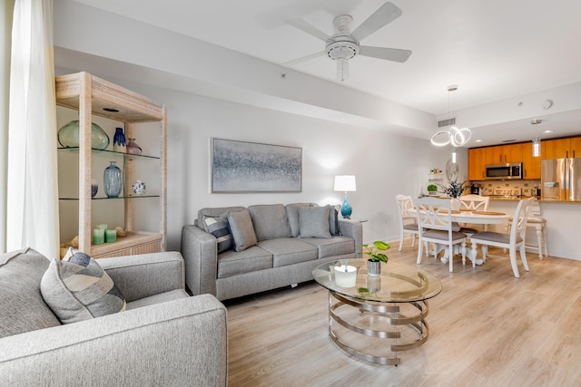 living room with light hardwood / wood-style flooring and ceiling fan with notable chandelier