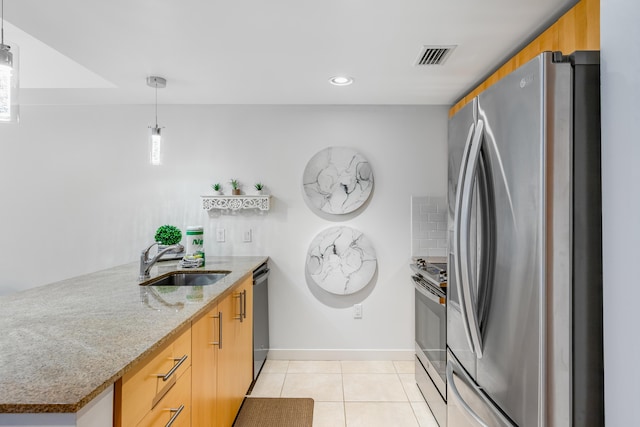 kitchen featuring decorative light fixtures, stainless steel appliances, light stone counters, sink, and light tile floors