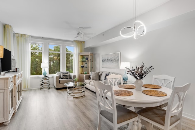 dining space featuring ceiling fan with notable chandelier and light wood-type flooring