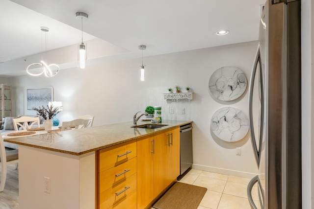 kitchen with appliances with stainless steel finishes, light tile floors, sink, decorative light fixtures, and a chandelier