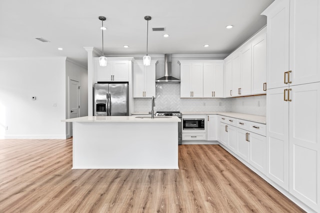 kitchen with decorative light fixtures, stainless steel appliances, light hardwood / wood-style floors, wall chimney range hood, and white cabinetry