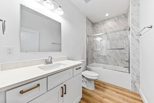 full bathroom featuring hardwood / wood-style floors, toilet, shower / bath combination with glass door, and large vanity