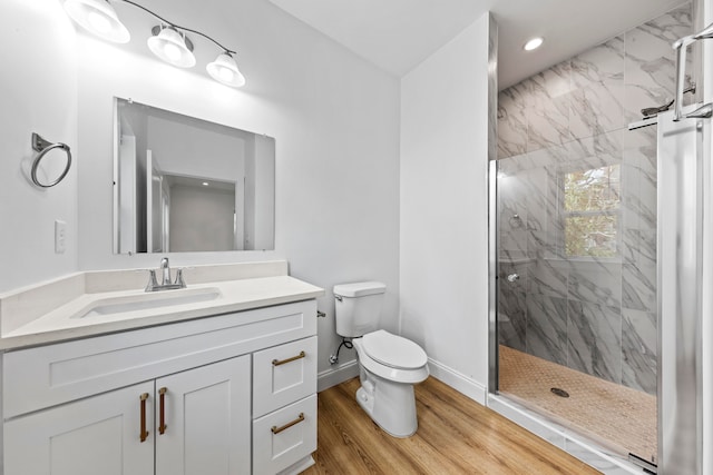 bathroom with a shower with door, hardwood / wood-style floors, vanity, and toilet