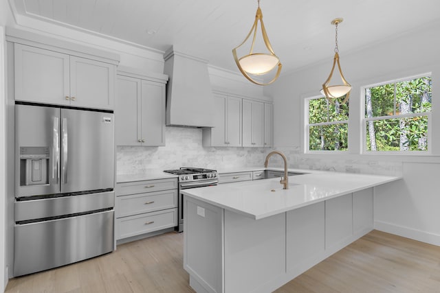 kitchen featuring hanging light fixtures, ornamental molding, sink, light hardwood / wood-style flooring, and appliances with stainless steel finishes