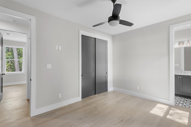 unfurnished bedroom with a closet, light wood-type flooring, ceiling fan, ensuite bath, and sink