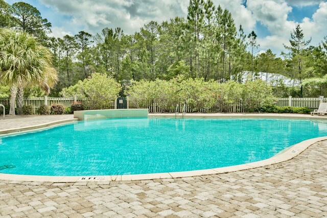 112 S Magnolia Beach Way, Santa Rosa Beach, FL 32459 - community pool featuring a fenced backyard, a patio area, and view of wooded area