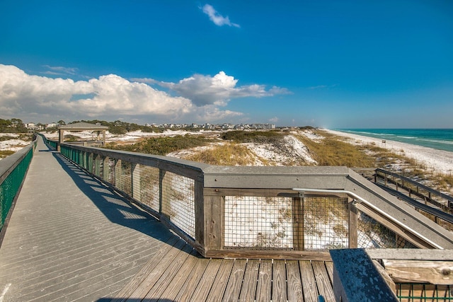 view of dock featuring a beach view and a water view