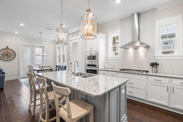 kitchen featuring white cabinets, appliances with stainless steel finishes, backsplash, and wall chimney exhaust hood