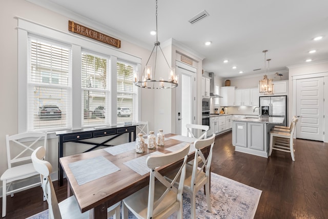 dining space featuring a chandelier, crown molding, dark hardwood / wood-style flooring, and sink