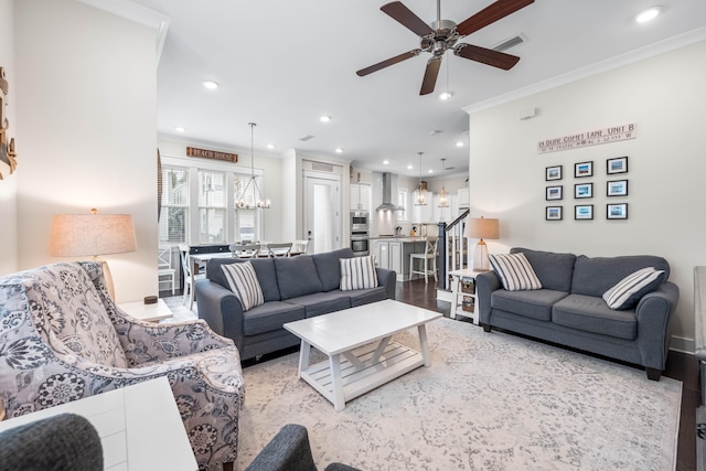 living room featuring ornamental molding, ceiling fan with notable chandelier, and light wood-type flooring