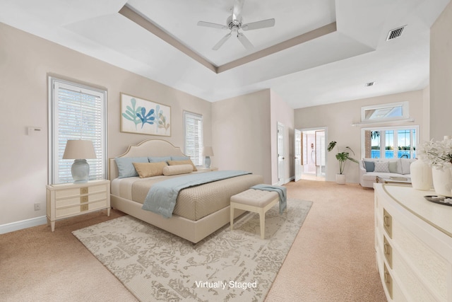 bedroom featuring light carpet, a tray ceiling, and ceiling fan