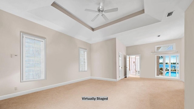 carpeted empty room featuring ceiling fan and a tray ceiling