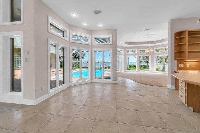 interior space featuring light tile patterned flooring, a raised ceiling, an inviting chandelier, and a wealth of natural light