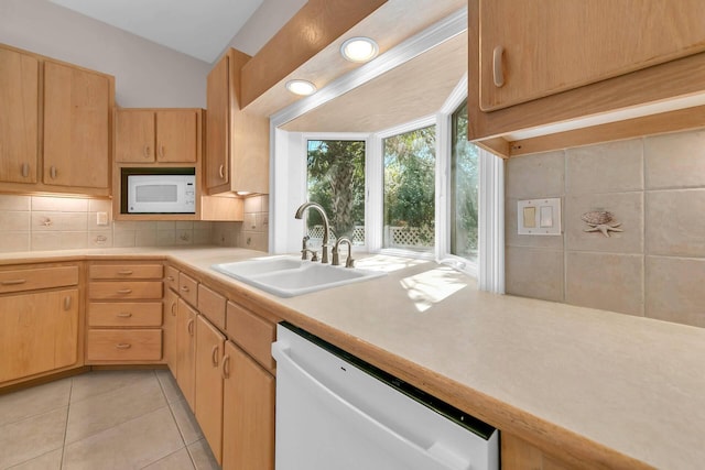 kitchen with light tile patterned floors, white appliances, sink, backsplash, and light brown cabinetry