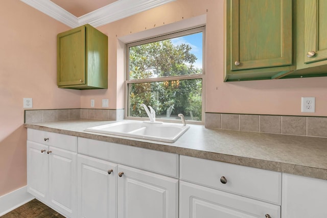 kitchen with white cabinetry, sink, and ornamental molding