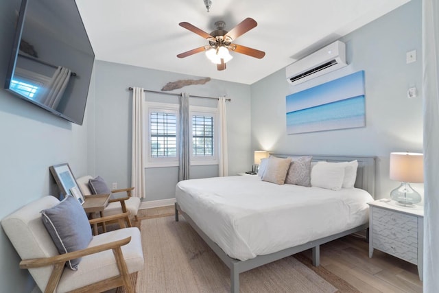 bedroom featuring ceiling fan, light wood-type flooring, and an AC wall unit