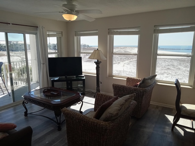 living room with ceiling fan, a water view, and dark hardwood / wood-style floors