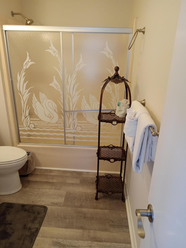 bathroom featuring enclosed tub / shower combo, toilet, and hardwood / wood-style floors