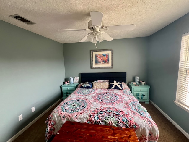 bedroom with ceiling fan, dark carpet, and a textured ceiling