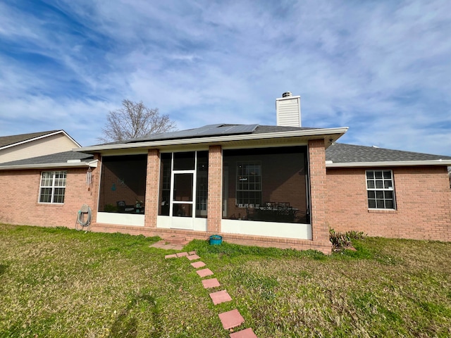 back of property featuring a sunroom and a lawn