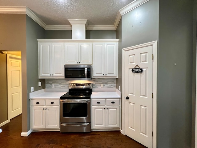 kitchen featuring decorative backsplash, ornamental molding, dark hardwood / wood-style flooring, white cabinetry, and appliances with stainless steel finishes