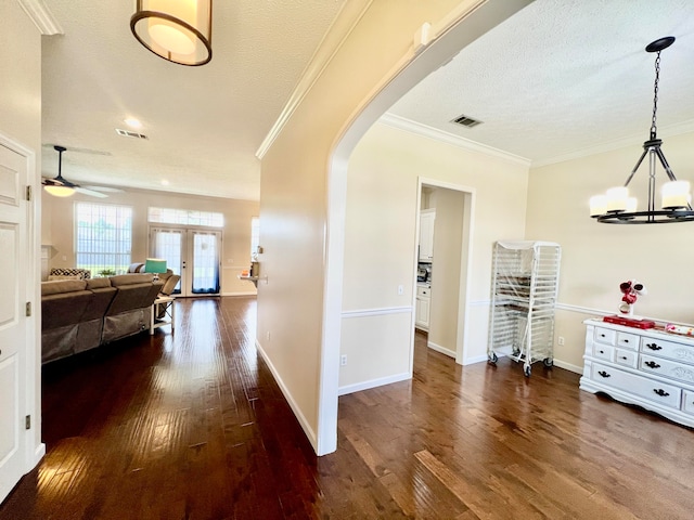 hallway with dark wood-type flooring, french doors, ornamental molding, and a textured ceiling