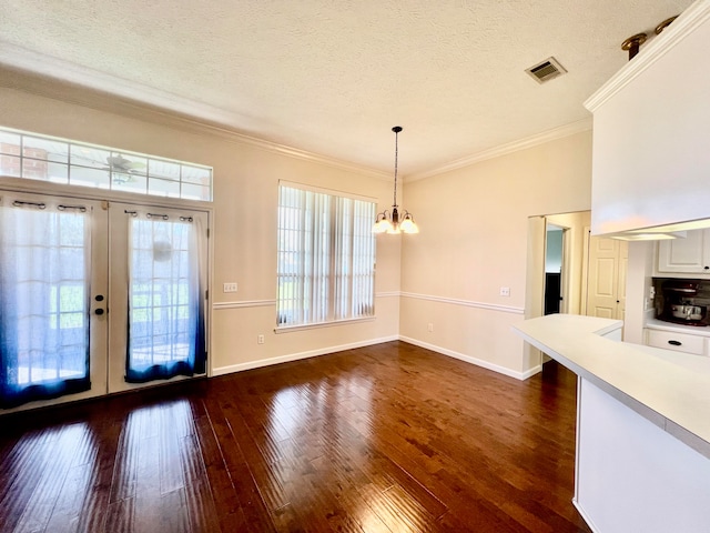 interior space with french doors, dark hardwood / wood-style floors, a chandelier, ornamental molding, and a textured ceiling