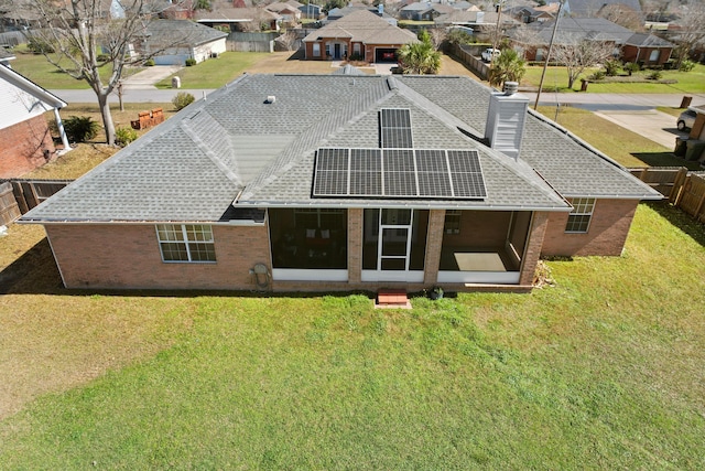 rear view of house with a lawn, solar panels, and a sunroom