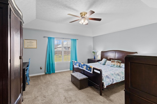 carpeted bedroom with a tray ceiling, ceiling fan, and a textured ceiling