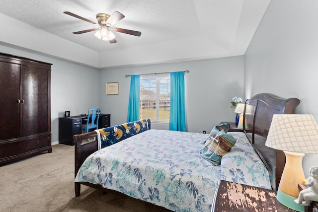 bedroom with a tray ceiling, light carpet, a textured ceiling, and ceiling fan