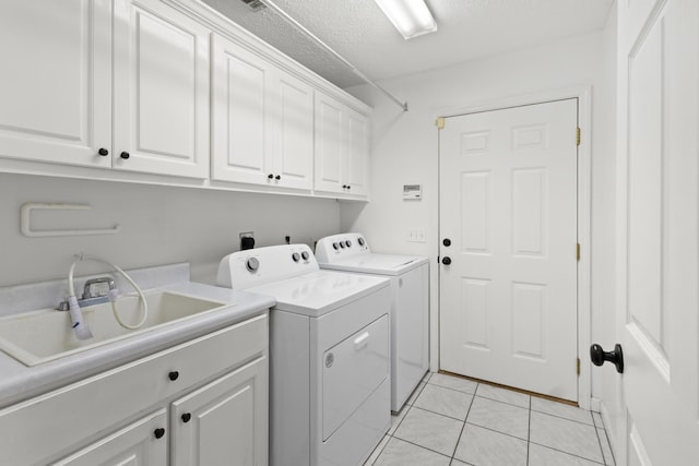 laundry room with cabinets, sink, washer and dryer, a textured ceiling, and light tile patterned flooring