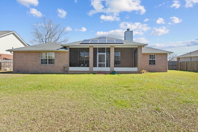 back of property with a lawn, solar panels, and a sunroom