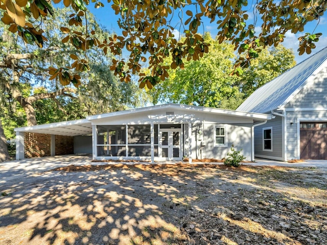 rear view of property with a carport and a sunroom