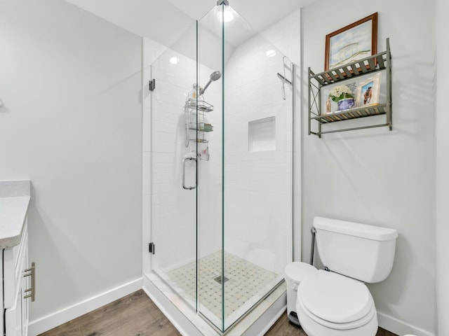 bathroom with wood-type flooring, vanity, toilet, and a shower with door