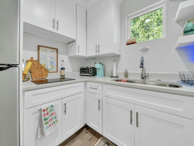 kitchen with stainless steel refrigerator, sink, white cabinets, and light hardwood / wood-style floors