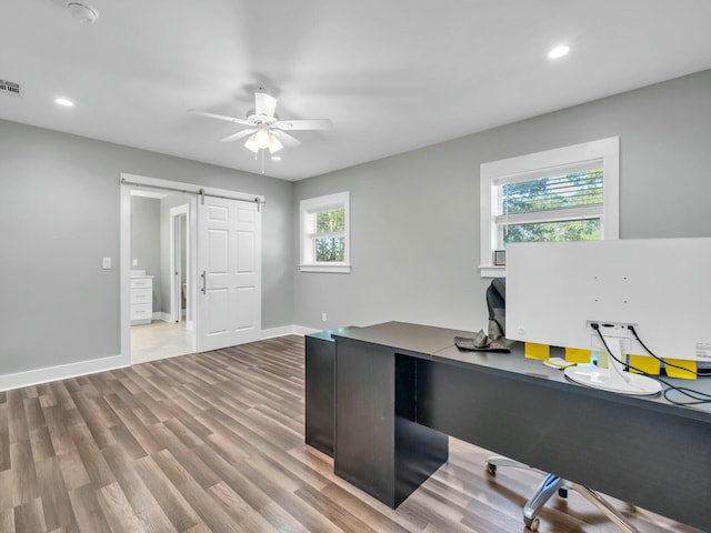 office space featuring a barn door, ceiling fan, and hardwood / wood-style flooring