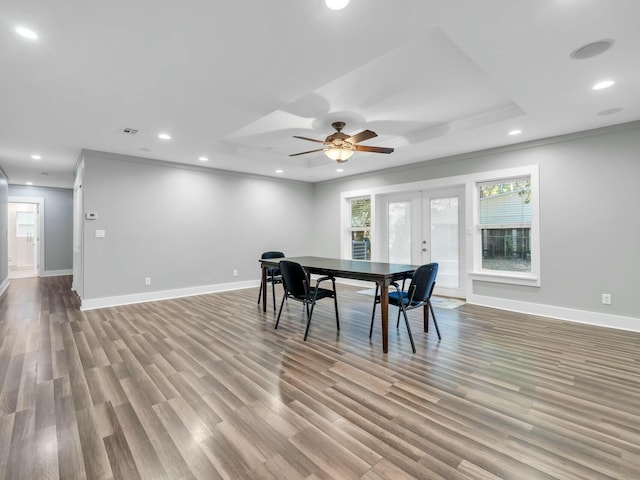 dining area featuring ornamental molding, light wood-type flooring, french doors, and a tray ceiling