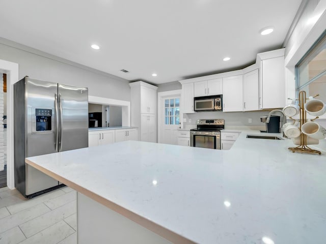 kitchen featuring kitchen peninsula, stainless steel appliances, white cabinets, and sink