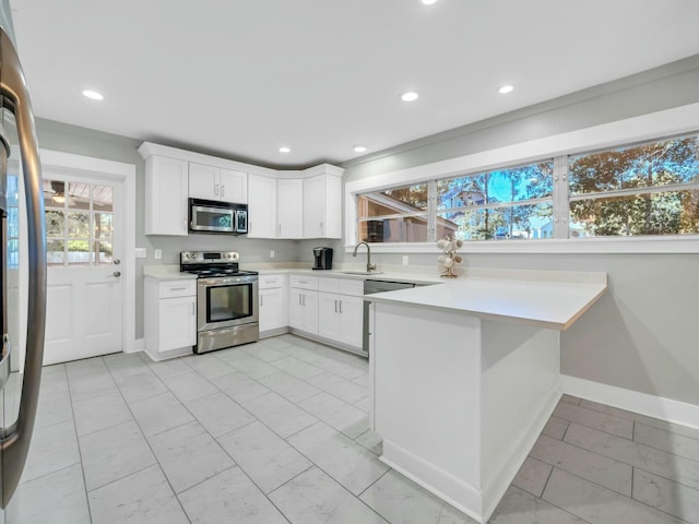 kitchen featuring white cabinetry, sink, stainless steel appliances, a kitchen breakfast bar, and kitchen peninsula