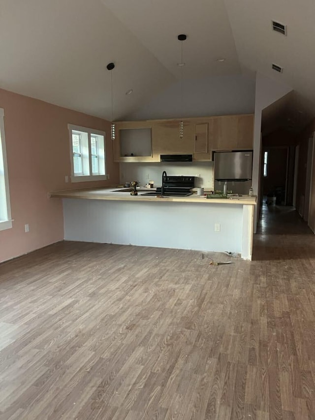 kitchen with pendant lighting, stainless steel refrigerator, electric range, wood-type flooring, and ventilation hood