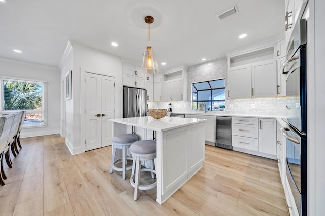 kitchen with a center island, white cabinets, tasteful backsplash, decorative light fixtures, and a healthy amount of sunlight