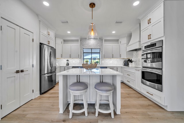 kitchen with a center island, custom range hood, stainless steel appliances, and light wood-type flooring