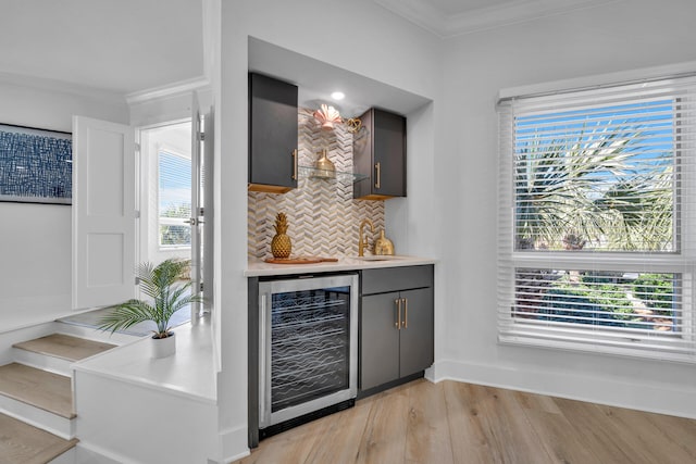 bar featuring backsplash, a healthy amount of sunlight, light hardwood / wood-style floors, and beverage cooler