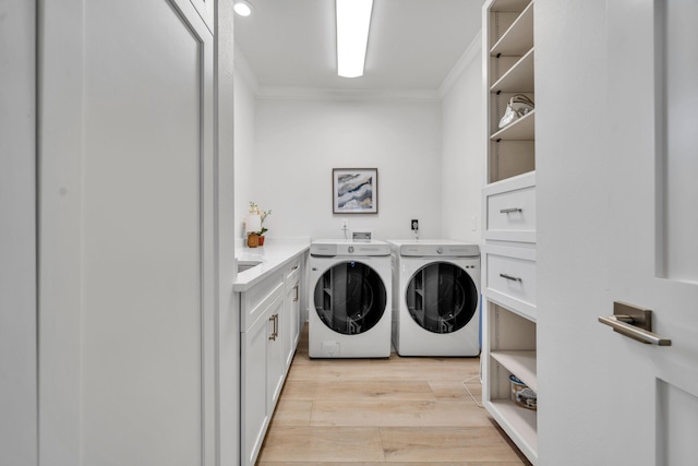 clothes washing area featuring light hardwood / wood-style floors, washing machine and dryer, crown molding, and cabinets