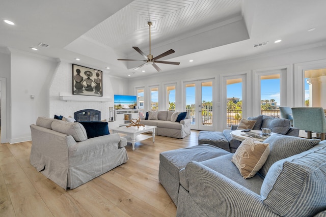 living room with light hardwood / wood-style flooring, a brick fireplace, ceiling fan, and a wealth of natural light